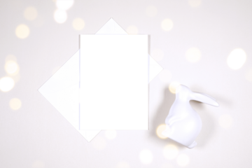 Vertical greeting card party invitation product mockup. Happy Easter theme product mockup. Minimal styling with bunny rabbit against a bokeh party lights background. Negative copy space.