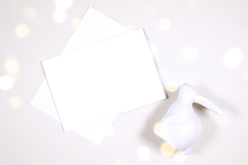 Horizontal greeting card party invitation product mockup. Happy Easter theme product mockup. Minimal styling with bunny rabbit against a bokeh party lights background. Negative copy space.