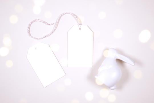 Gift tag thank you card product mockup. Happy Easter theme product mockup. Minimal styling with bunny rabbit against a bokeh party lights background. Negative copy space.