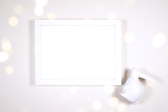 Horizontal artwork wall art picture frame product mockup. Happy Easter theme product mockup. Minimal styling with bunny rabbit against a bokeh party lights background. Negative copy space.