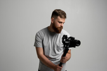Side view of professional bearded videographer, cinematographer, cameraman using camera on gimbal stabilizer, steadicam on white background.