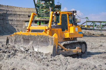 Crawler bulldozer working on construction site or quarry. Mining machinery moving clay, smoothing...