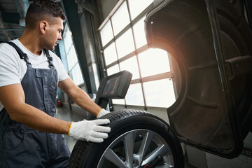 Man testing technical condition of car wheel