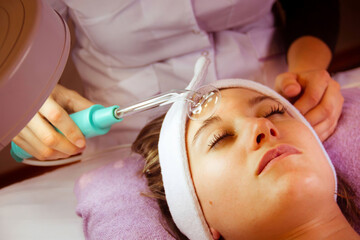 young woman performing cleansing treatment peeling rejuvenating facial treatment in a SPA. ...
