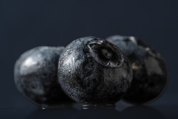 three fresh berries of ripe blueberries on black background