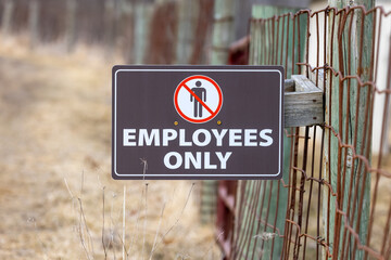 Employees only sign on the farm fence .