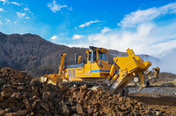 Big crawler dozer working on construction site or quarry. Mining machinery moving clay, smoothing gravel surface for new road. Earthmoving, excavations, digging on soils © Leszek Szelest