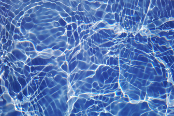 Bluewater waves on the surface ripples blurred. Defocus blurred transparent blue colored clear calm water surface texture with splash and bubbles. Water waves with shining pattern texture background.