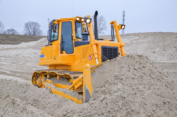 Crawler bulldozer working on construction site or quarry. Mining machinery moving clay, smoothing...