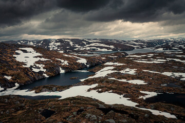 Fototapeta na wymiar Landscape from above around Lysefjord in Rogaland with lakes and snow in Norway, dark cloudy sky