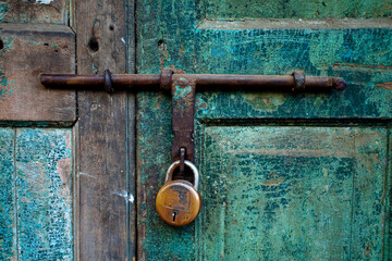 A close up photo of a brass lock on an old blue green shop door.