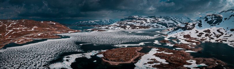 Snowy landscape of Hardangervidda national park with mountains and icy lakes in Norway, from above