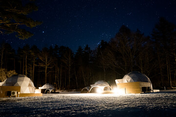 夜のキャンプ場のグランピング施設と冬の星空
