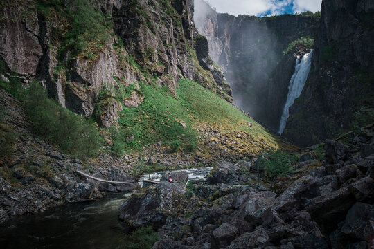 Woman hiking to Voringsfossen waterfall in a valley at Hardangervidda National Park in Norway