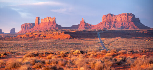 Monument Valley at sunset, panoramic photo with long road to the right