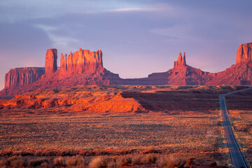 Monument Valley at sunset, panoramic photo with long road off to the right