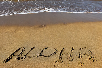 Word aloha written on the sand of Hawaii beach