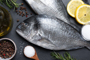 Fresh dorado fish and ingredients on black slate background, flat lay