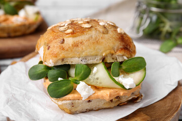 Delicious sandwich with hummus, microgreens and cucumber slices on wooden board, closeup