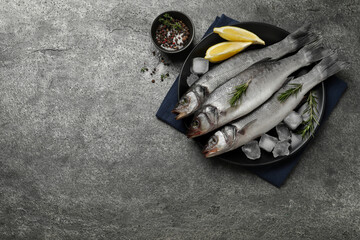 Sea bass fish and ingredients on grey table, flat lay. Space for text