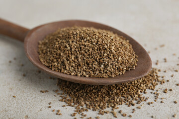 Spoon of celery seeds on light grey table, closeup