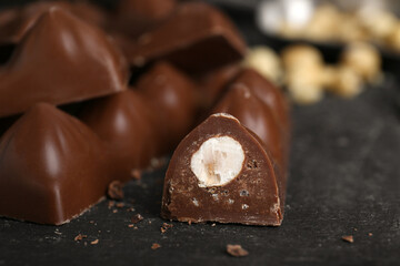 Tasty chocolate bars with nuts on black table, closeup