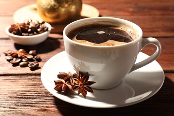 Aromatic hot coffee with anise stars and beans on wooden table