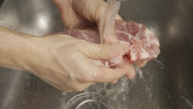 man hands wash meat steak in the sink for grill stuttering. HLG3, BT.2020. 