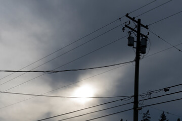 A silhouette image of a residential power transformer against a stormy summer sky.
