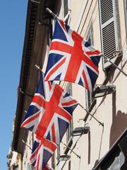 United Kingdom flags fly on a building. Outdoors, sunlight.