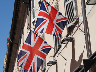 United Kingdom flags fly on a building. Outdoors, sunlight.