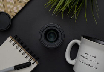 Make More Adventures: Overhead flat lay of a 30mm f1.4 digital prime camera lens surrounded by personal items on a black background. - obrazy, fototapety, plakaty