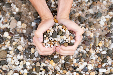 A man makes a heart out of pebbles. Heart on the sea. Romantic photo. Holiday on February 14 on a journey to the ocean.