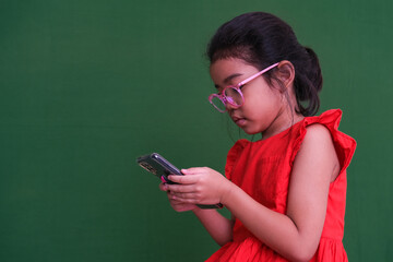 Little girl in her red dress and glasses busy playing game on her gadget