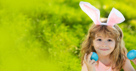 Obraz na płótnie Canvas Easter bunny child boy with cute face. Kids hunting easter eggs. Children activity for Easter in nature. Horizontal photo banner for website header design with copy space.