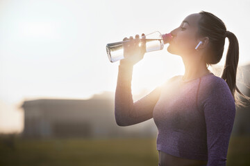Fitness, sunset and woman drinking water bottle after training workout, exercise and outdoor cardio running. Thirsty young athlete, sports hydration and nutrition for wellness, healthy body or energy