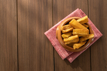 A portion of fried maniocs ( Mandiocas ) on a wooden table, traditional brazilian food.