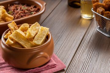 A portion of fried maniocs ( Mandiocas ) on a wooden table, traditional brazilian food.