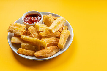 A portion of fried maniocs ( Mandiocas ) on a on a Yellow background, traditional brazilian food
