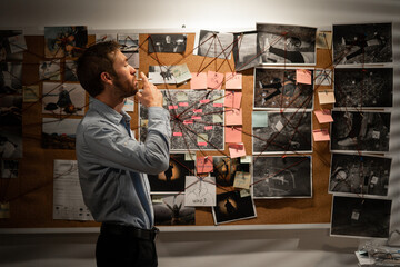 Detective analyzing information of crime on investigation board.