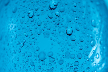 Water pouring from a plastic bottle into a glass beaker on a blue background