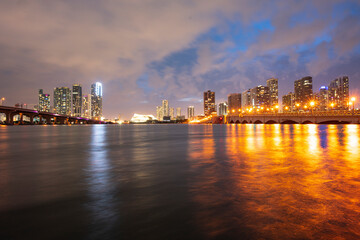 Naklejka premium Miami city skyline panorama at night skyscrapers and bridge over sea with reflection