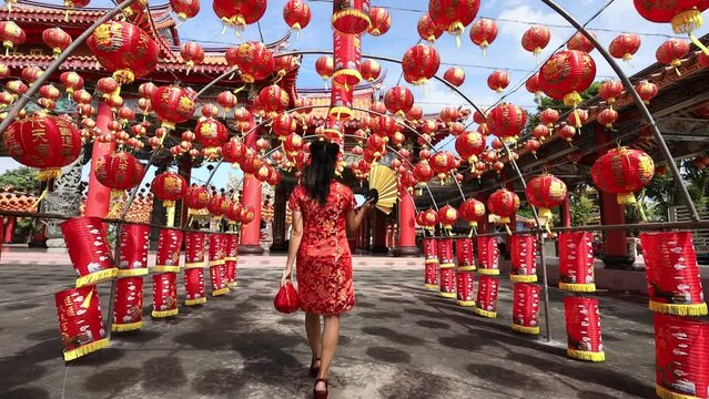 Rear view of Asian woman in red cheongsam qipao dress is visiting the Chinese Buddhist temple during lunar new year for traditional culture concept the Chinese word means blessing for all