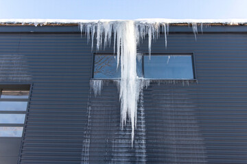 Huge dangerous ice icicles hanging from the edge of the hangar roof