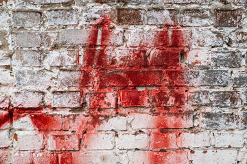 Texture of old brick painted in white, worn wall, smeared with red paint, background