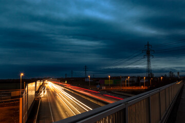 Fototapeta na wymiar Autobahn mit Strommasten in der Abenddämmerung, Langzeitbelichtung