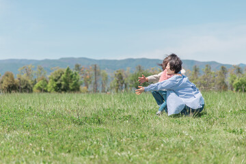 草原・公園で両親に走って抱きつく活発な子供（女の子）
