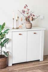 Cozy living room - white chest of drawers, Christmas decor in a vase in Scandinavian minimalist style