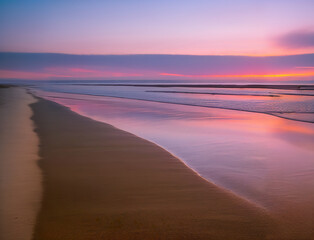 sunset on the beach, purple and red sky, peaceful  beach with calm waves