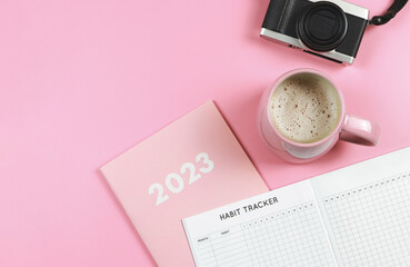  flat lay of habit tracker book on pink diary or planner 2023, pink cup of coffee and digital...